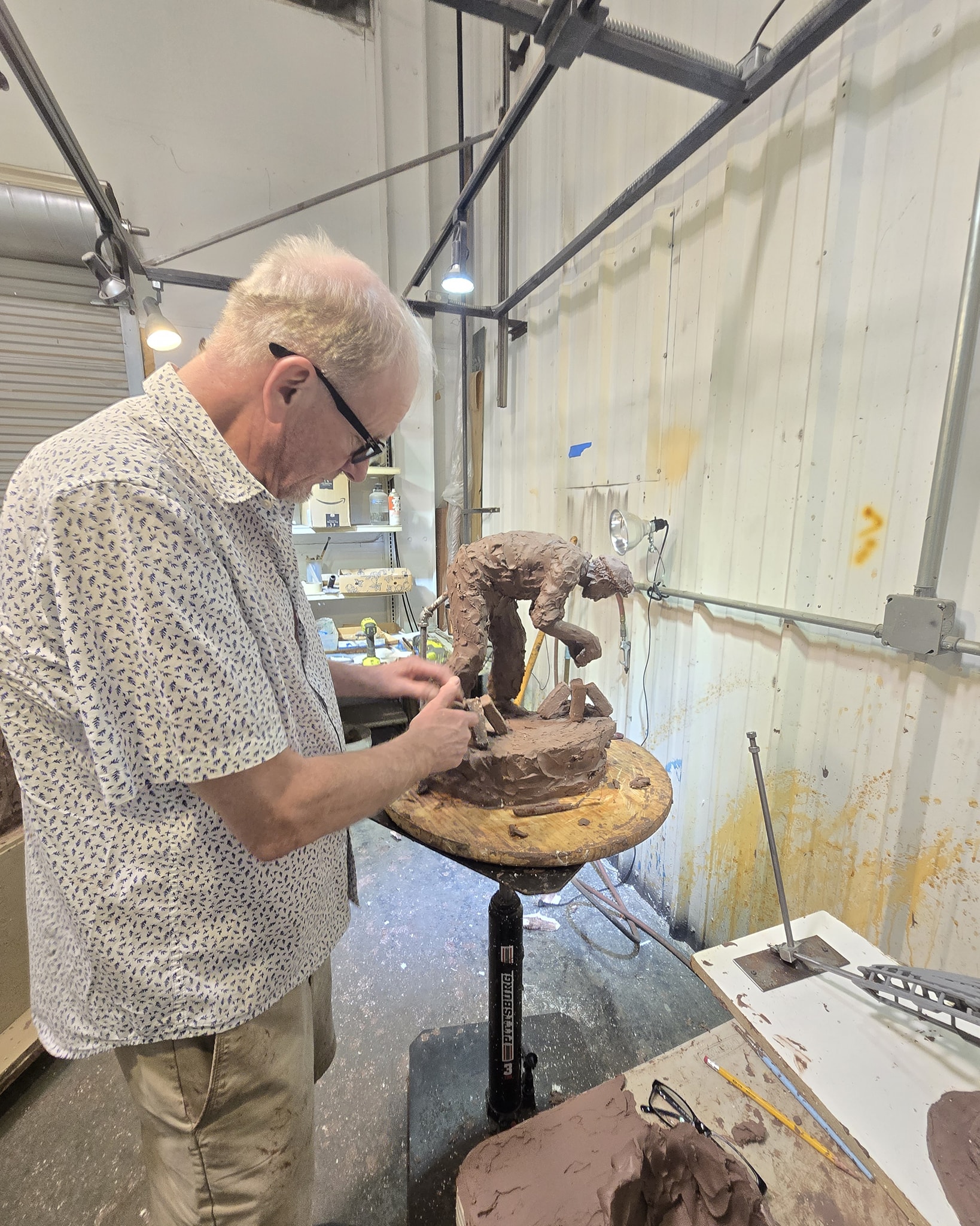 Handsome male artist sculpting detailed clay figure in studio.